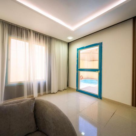 Mirada Gold Jizan - Resort & Private Pools Zewnętrze zdjęcie The photo shows a modern interior space that appears to be a room in a home or a building. There is a large window with sheer curtains letting in natural light, which contributes to a bright and airy atmosphere. On one side of the room, there is a sl