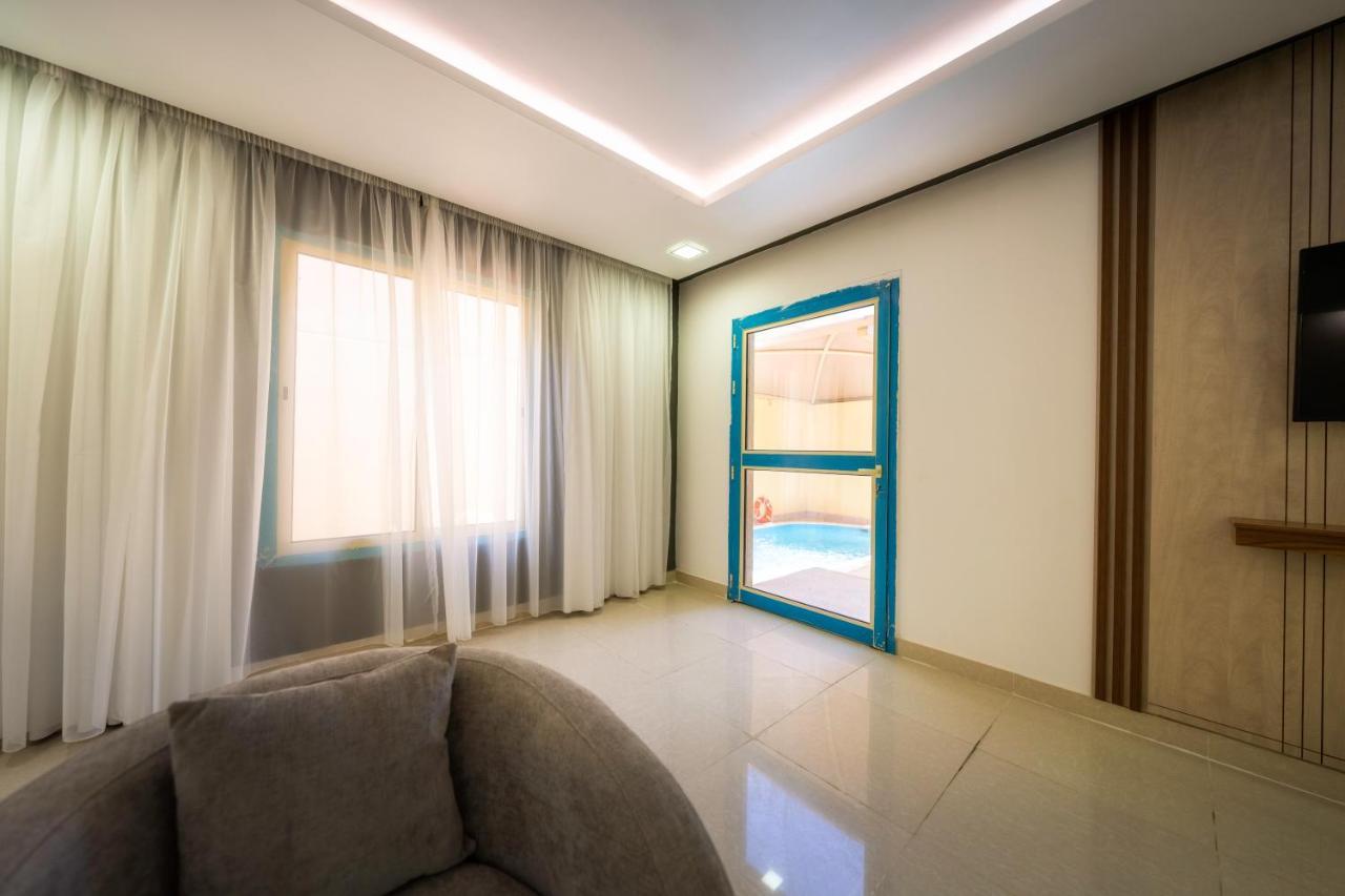 Mirada Gold Jizan - Resort & Private Pools Zewnętrze zdjęcie The photo shows a modern interior space that appears to be a room in a home or a building. There is a large window with sheer curtains letting in natural light, which contributes to a bright and airy atmosphere. On one side of the room, there is a sl